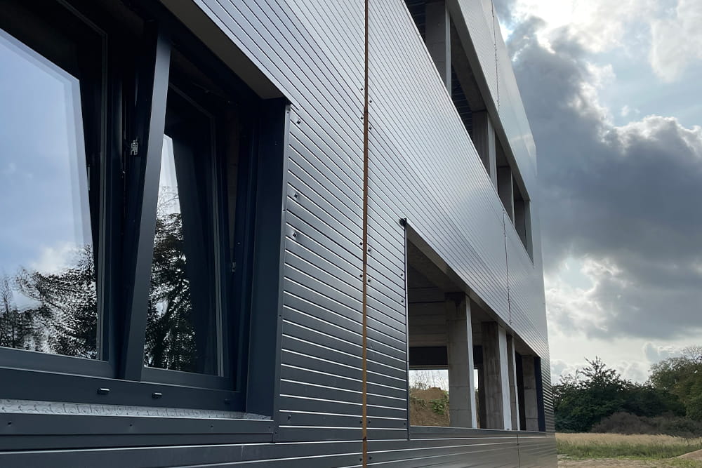 Außenansicht entlang des Gebäudes fotografiert, wo einige Fenster eingebaut sind und andere noch fehlen.